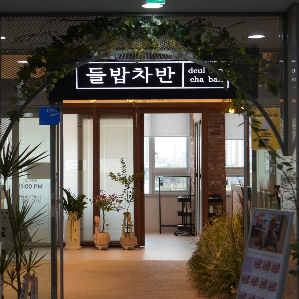 식물 아치와 들밥차반 간판이 있는 루원시티가정점 입구